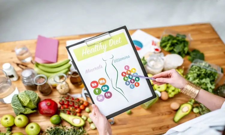 Gut-Friendly Metabolic Eating Foods List A person holds a clipboard titled "Healthy Diet" with a diagram of minerals and vitamins, surrounded by fresh fruits and vegetables on a wooden table, about gut-friendly metabolic eating